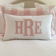 a pink and white pillow with the word here on it in cursive font