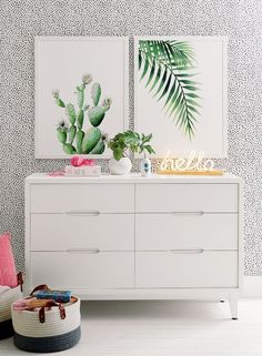 a white dresser sitting next to a wall with two paintings on it's sides