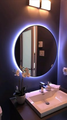 a bathroom sink under a round mirror with lights