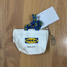 a small white bag with a blue and yellow lanyard on it, next to a keychain