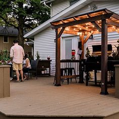 a man is standing on the deck next to an outdoor bbq and grill area