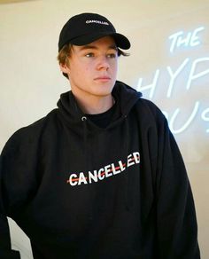 a young man wearing a black hooded sweatshirt and hat