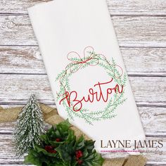 a white towel with the word burton on it next to a christmas wreath and holly