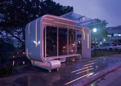 a bus stop sitting on the side of a road next to a parking lot at night