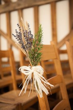 a bouquet of lavenders tied to a wooden chair in front of a row of chairs