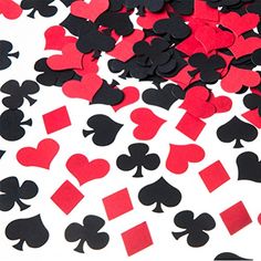 black and red playing cards are scattered on a white tablecloth with confetti in the shape of spades