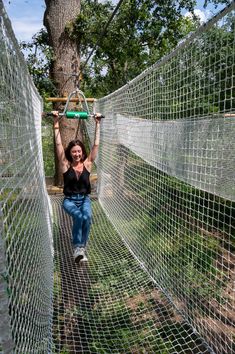 a woman is walking on a rope bridge