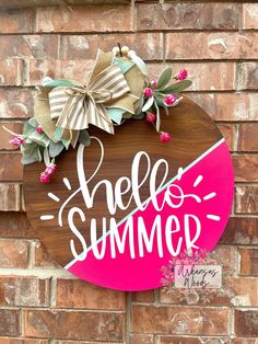 a wooden sign that says hello summer hanging on the side of a brick wall with flowers