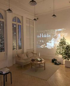 a living room filled with furniture and a christmas tree in front of a projector screen