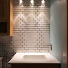 an empty bathroom with three lights above the sink