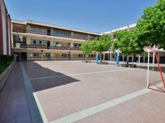 an empty basketball court in the middle of a building with trees and benches around it