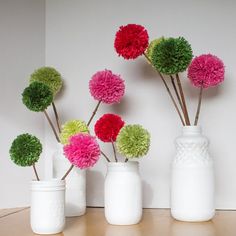 four white vases with different colored flowers in them