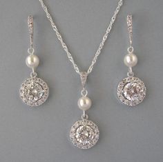 a necklace and earring set with pearls on a gray background, including a pendant