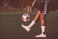 a man kicking a soccer ball on top of a field