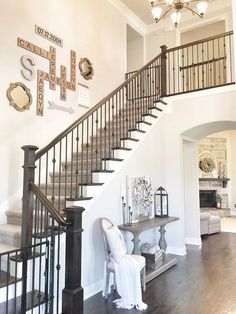 there is a stair case in the living room with white walls and wood floors, along with a chandelier that hangs from the ceiling