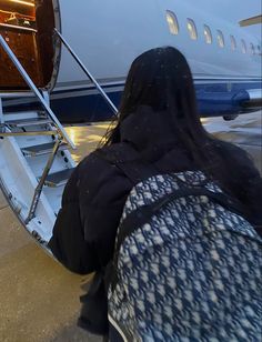 a woman is getting off an airplane with her back to the camera as she sits on the stairs