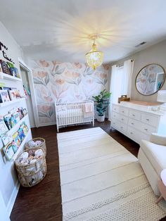 a baby's room with floral wallpaper and white furniture