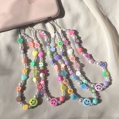 a bunch of beads that are laying on a bed next to a cell phone and an ipod