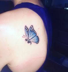 a blue butterfly tattoo on the back of a woman's shoulder