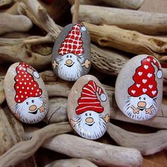 three gnomes painted on rocks sitting next to driftwood