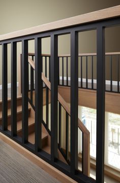 an empty room with wooden floors and black railings on the wall next to a window