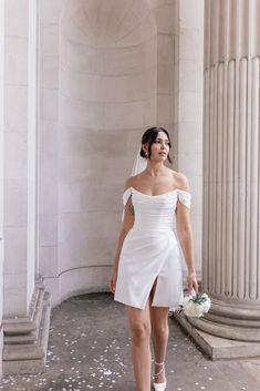 a woman in a white dress is walking down the street with flowers on her feet