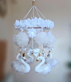 a chandelier with white flowers and two swans hanging from it's sides