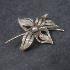 This beautiful flower brooch is sterling silver. Measurements: 1 5/16 by 1 7/8 inches Marks: Forstner, Sterling Condition: Excellent with patina The Forstner jewelry company was founded in 1920 in Irvington, New Jersey.  The  company later changed their name to the Forstner Jewelry Manufacturing Corporation. In 1980, the corporation ceased operations. Formal Flower Shaped Hallmarked Brooch, Classic Flower Brooches For Anniversary, Silver Flower Shaped Brooch Jewelry, Silver Floral Shape Brooch Jewelry, Silver Flower Shaped Brooch, Silver Floral Brooch, Vintage Sterling Silver Flower Brooches, Elegant Silver Flower Shaped Brooch, Vintage Silver Flower Brooches