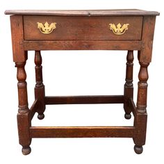 an old wooden table with two drawers on one side and gold handles on the other