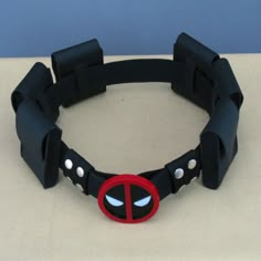 a black bracelet with a deadpool face on it's side and eyes painted red