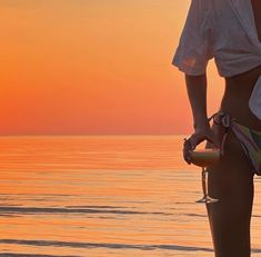 a woman standing on the beach at sunset