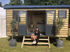 a woman sitting on a bench in front of a tiny house