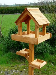 a wooden bird house sitting on top of a lush green field