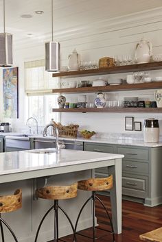 a kitchen with wooden stools and open shelving on the wall above the island