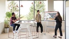 three people sitting at a table in an office