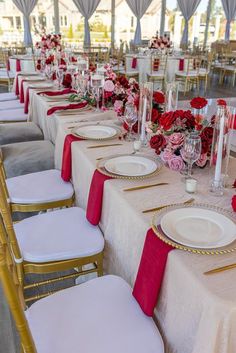 the tables are set with white and red linens, gold rimmed plates, silverware, and pink flowers