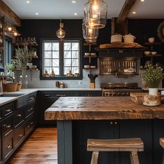 a kitchen with black cabinets and wooden counter tops, lights hanging from the ceiling over the island