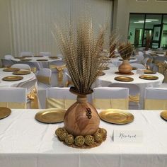 a vase with some dried plants in it on a table set up for a formal function