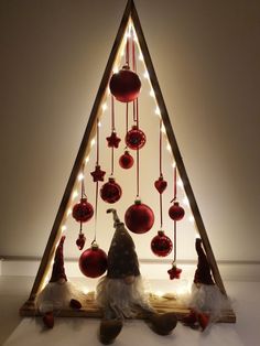 a christmas tree made out of wooden sticks and ornaments with lights around it, sitting on top of a white surface