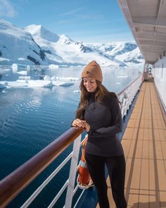 a woman standing on the deck of a ship looking at her cell phone and smiling