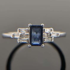 an engagement ring with a blue stone surrounded by baguettes