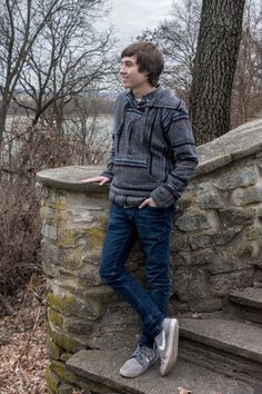 a young man standing on some steps in front of a tree and looking off into the distance