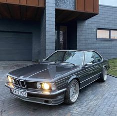 an old bmw is parked in front of a house