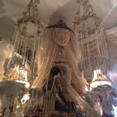 a chandelier hanging from the ceiling in a room with lots of white curtains