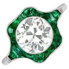 This ring has a 2.06-carat old European cut diamond with J color and VS1 clarity, surrounded by natural emeralds. The emerald halo extends to the shoulders and has an open-work under-gallery. The total emerald weight is approximately 0.75 carats. Ring Size: 6.5 US, Resizable Diamond Size: Approximately 11.77mm x 11.93mm Color: J Color Clarity: VS1 Metal: Platinum Stone: Diamond, Emerald Stone Cut: Old European Cut Style: Art Deco Diamond And Emerald Ring, Sapphire Cocktail Ring, Bijoux Art Nouveau, Engagement Ring Diamond Cut, Unusual Jewelry, Diamond Cocktail Rings, Art Nouveau Jewelry, Engagement Ring Cuts, European Cut Diamonds