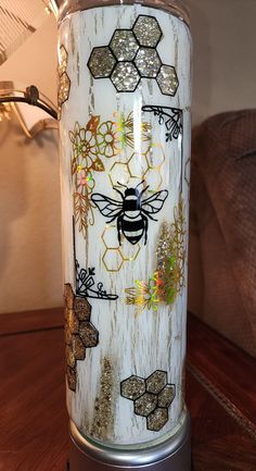 a vase with bees and flowers painted on it sitting on a table next to a lamp