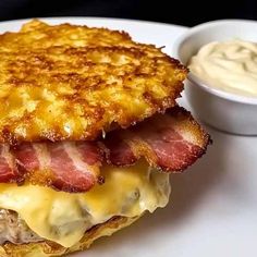 there is a sandwich with meat and cheese on it next to a bowl of mayonnaise