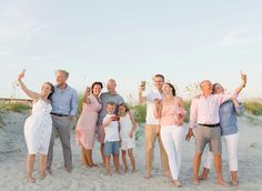 a group of people standing on top of a beach next to each other holding up cell phones