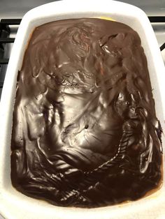 a white dish filled with chocolate frosting on top of a stove