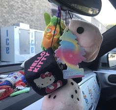 the stuffed animals are hanging from the car's rearview mirror holder, which is decorated with hello kitty and other cartoon characters